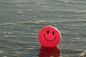 imagen de una pelota roja con una cara sonriente flotando el agua que explica que es la educación emocional