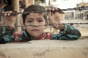 Foto de niño moreno triste son sus manos en un alambre que representa las heridas de la infancia para el artículo de Unicarl rogers