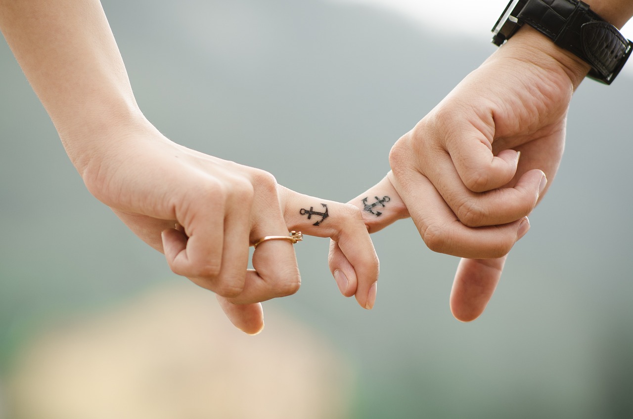 Foto de las manos juntas de un hombre y una mujer tomados de la mano para representar los estilos de apego en el artículo de la universudad Carl Rogers
