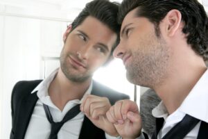 Foto de hombre narcisisita con traje mirandose al espejo