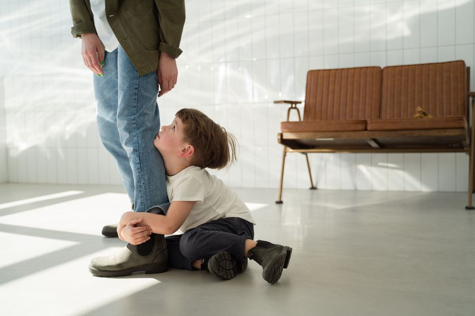 Foto de niño obligando a su papá a quedarse, sosteniendo su bota mientras llora.